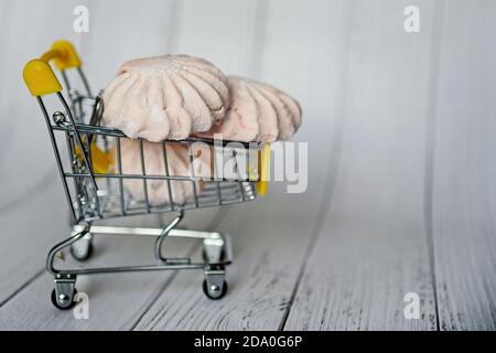 Wagen mit Marshmallows auf hellem Hintergrund. Kreative Idee für Verkauf, Promotion oder Konzept für Cyber Monday oder Black Friday. Stockfoto