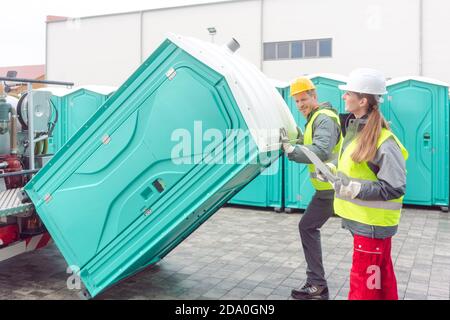 Mitarbeiter laden mobile Toiletten auf Lkw Stockfoto