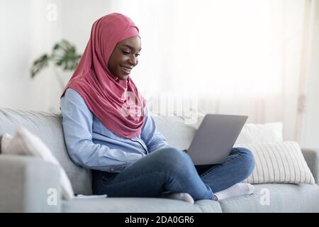 Internet-Shopping. Black Muslim Lady Kaufende Dinge Online Mit Laptop Zu Hause Stockfoto