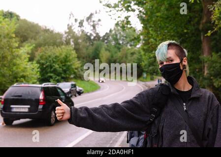 Ernsthafter Anhalter in Schutzmaske am Straßenrand in Monte Cabezon Naturdenkmal von Sequoias in Kantabrien und Anhalter mit Ausdehnbarem Stockfoto