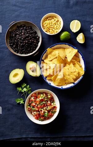 Zutaten zum Kochen von Chilaquiles - schwarze Bohnen, Tortilla-Chips, Mais und Salsa Stockfoto
