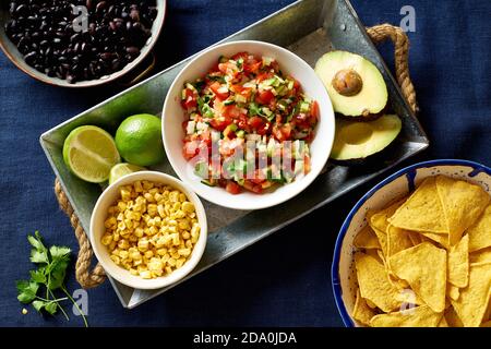 Zutaten zum Kochen von Chilaquiles - schwarze Bohnen, Tortilla-Chips, Mais und Salsa Stockfoto