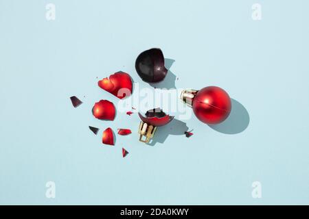 Ganze und gebrochene rote Weihnachtskugeln auf blauem Hintergrund angeordnet Im hellen Studio Stockfoto