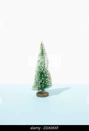 Miniatur von dekorativen Weihnachtsbaum auf Tisch im Studio platziert Auf blauem Hintergrund Stockfoto