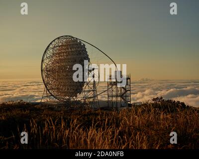 Atemberaubende Sicht auf moderne Teleskope auf dunklem Berggipfel gegen Wolken Und Sonnenlicht während Sonnenuntergang am astronomischen Observatorium auf der Insel Von La Palma Stockfoto