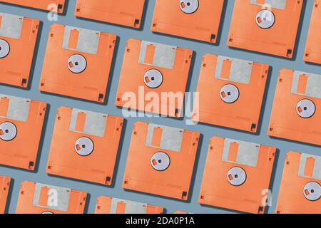 Draufsicht Layout mit einem Satz von vintage orange Computer Floppy Festplatten in Zeilen auf grauem Hintergrund angeordnet Stockfoto