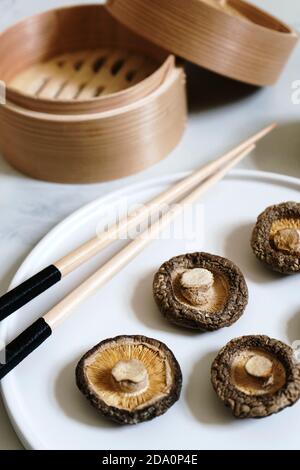 Draufsicht auf appetitlich trockene Shiitake-Pilze in Reihe angeordnet Auf Bambusmatte auf Tisch Stockfoto