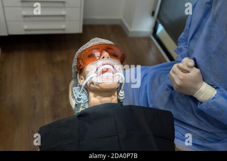 Von oben beschnitten unkenntlich professionellen Stomatologen sitzen in der Nähe des Patienten mit expander im Mund in der modernen Klinik Stockfoto