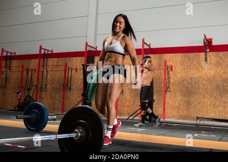 Niedriger Winkel der entzückten weiblichen Gewichtheber Vorbereitung Langhantel zu tun Übungen während des Trainings im Fitnessstudio Stockfoto