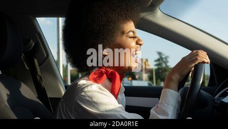 Seitenansicht der afroamerikanischen Fahrerin mit Auto und Glücklich lachend mit geschlossenen Augen Stockfoto
