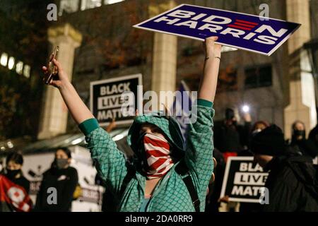 Portland, USA. November 2020. Eine Frau, die ein Dinosaurier-Kostüm trägt, winkt ein Biden-Harris-Zeichen. Eine improvisierte Tanzparty, die die Niederlage von Donald Trump durch Joseph Biden feierte, brachte am Abend des 7. November 2020 Hunderte von tanzenden Parties, einen Diskjockey und kostümierte Zelebranten nach Portland, Oregon's Pioneer Square. (Foto: John Rudoff/Sipa USA) Quelle: SIPA USA/Alamy Live News Stockfoto