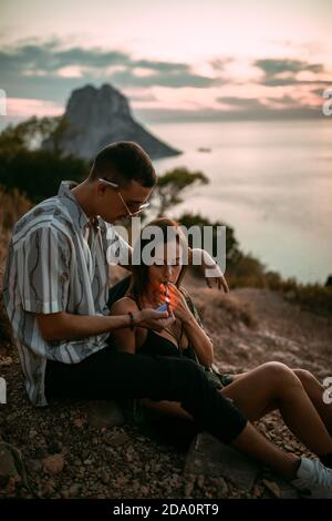 Seitenansicht eines ruhigen Mannes, der während der Zeit eine Zigarette anzündet Chillen an der Küste bei Sonnenuntergang Stockfoto