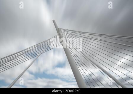 Von unten von weißen zeitgenössischen Hängebrücke mit hoher Säule Verbinden vieler Kabel mit blauem Himmel Stockfoto