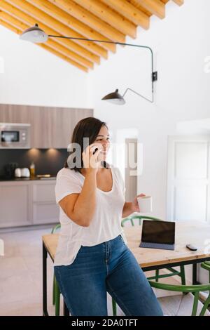 Nahaufnahme einer Frau, die mit einer Tasse Kaffee telefoniert Stockfoto