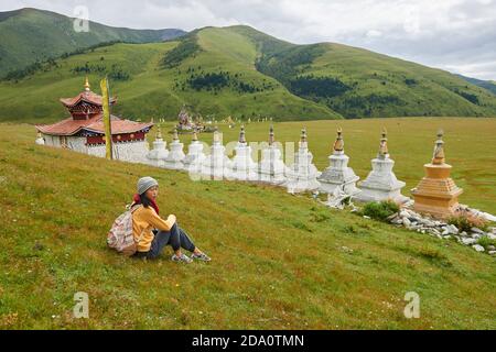 Seitenansicht volle Länge der asiatischen weiblichen Rucksacktouristen genießen Urlaub Nahe orientalischer Schrein im grünen Tal in China Stockfoto