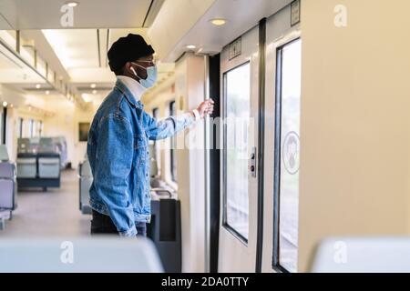 Von unten angenehmer bärtiger ethnischer Arbeiter in Uniform, der das Paket trug, während er bei der Arbeit das Mobiltelefon benutzte Stockfoto