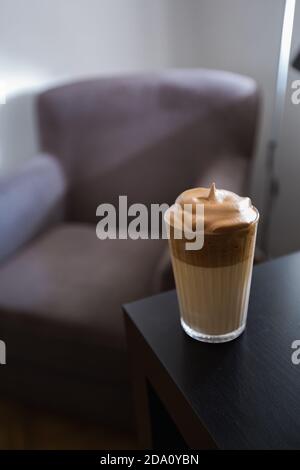 Hoher Winkel von leckeren Dalgona Kaffee im Glas platziert auf Holztisch im modernen Wohnzimmer zu Hause Stockfoto
