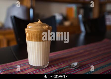 Ein Glas aromatischen kalten Dalgona Kaffee serviert auf dem Tisch in Dunkles Zimmer Stockfoto