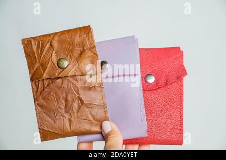 Gruppe bunte Geldbörse aus Leder Haut auf weißem Hintergrund.drei modische moderne Leder Tasche Brieftaschen in der Hand, Nahaufnahme, Messing Schnappschüsse, helle Farben Stockfoto