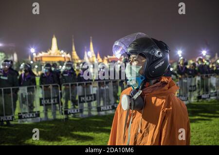 Bangkok, Thailand. November 2020. Ein Demokratieprotegter mit Helm steht bei einer Anti-Regierungsdemonstration in der thailändischen Hauptstadt neben den Polizeibeamten vor dem Großen Palast. Prodemokratische Demonstranten gingen auf die Straßen am Democracy Monument, um in Richtung des Großen Palastes zu marschieren, um dem thailändischen König Maha Vajiralongkorn (Rama X) einen Brief zu überbringen. Die Demonstranten wurden von der thailändischen Polizei getroffen, die Stadtbusse und Stacheldraht benutzte, um die Straße zu blockieren. Und Wasserkanonen, um die Menge in Sanam Luang vor dem Großen Palast zu zerstreuen. Kredit: SOPA Images Limited/Alamy Live Nachrichten Stockfoto