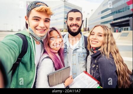 Selfie-Zeit! Vier internationale Studenten mit strahlenden Lächeln posieren für Selfie außerhalb der Schule - gesammelt, fröhlich, smart und erfolgreich Stockfoto