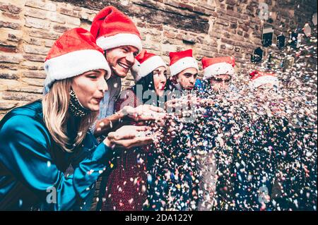 Gruppe von glücklichen Freunden mit Gesichtsmaske feiern alle zusammen Konfetti blasen und Spaß haben in covid-19 Zeit - Konzept Über Glück und freudiges Neues Stockfoto