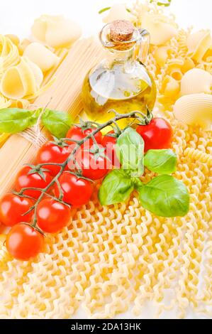 Italienische Pasta mit frischen Tomaten, Olivenöl und Basilikum. Makkaroni mit Zutaten zum Kochen. Italienisches Essen. Stockfoto