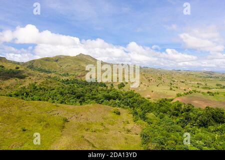 Grüne Hügel und blauer Himmel mit Wolken. Schöne Landschaft auf der Insel Luzon, Luftbild. Berglandschaft bei sonnigem Wetter. Stockfoto