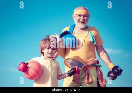 Senioren und Kinder trainieren am blauen Himmel. Sportübungen für Kinder. Porträt eines gesunden Vaters und eines Sohnes, der auf blauem Himmel auf dem Hintergrund arbeitet. Stockfoto