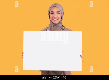 Muslim Lady Holding Blank Poster Für Text Auf Gelbem Hintergrund Stockfoto