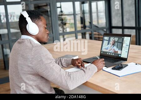 Afrikanischer Geschäftsmann mit Kopfhörern, Videoanrufe, die Webinar ansehen. Stockfoto