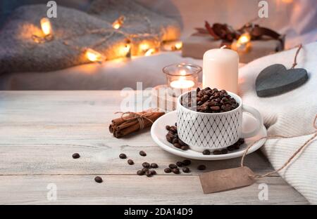 Eine Tasse Kaffee voller Kaffeebohnen auf einem gemütlichen Abend Urlaub Hintergrund mit Lichtern. Stockfoto