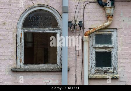 Ein rostiger alter Abflussschlauch und verfaulte Fensterrahmen an einem alten Gebäude, das etwas Pflege, Aufmerksamkeit und Wartung braucht. Stockfoto