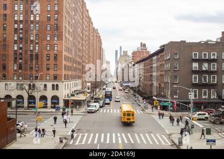 West 23rd Street und 10th Avenue von der High Line aus gesehen, New York City, NYC März 2019. Ein Schulbus überquert die Kreuzung Stockfoto