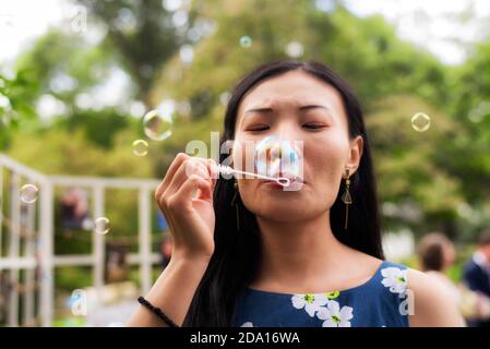 Eine chinesische Frau bläst an einem Sommertag in Connecticut Blasen nach draußen. Stockfoto