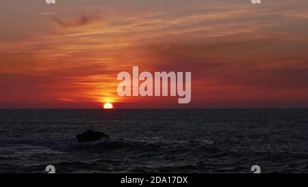 Majestätischer Sonnenuntergang mit dramatischem Himmel und orange und rot gefärbten Wolken über dem Horizont des Atlantiks an der Küste von Essaouira, Marokko, Afrika. Stockfoto