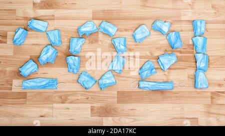 Draufsicht der Zahlen 2021 aus medizinischen Gesichtsschutzmasken. Gebrauchte Hygienic Masken verstreut auf dem Boden Forming 2021. Happy New Year Konzept. Jahr Stockfoto