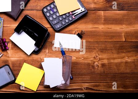 Business Zubehör und Ideen Konzept. Schreibwaren und Taschenrechner. Geldbörse und Handy auf Holzhintergrund. Visitenkarten im Kartenhalter, Ordner, Stift und Wäscheklammern in der Nähe von gelben Aufklebern Stockfoto