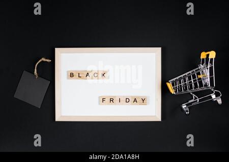 Angebot „Black Friday“. Mini-Warenkorb im Rahmen auf schwarzem Hintergrund. Stockfoto