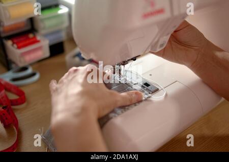 Frau Hände mit der Nähmaschine, um das Gesicht zu nähen Maske Stockfoto