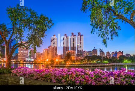 Lake in City Park unter Wolkenkratzern in der Nacht. Benjakiti Park in Bangkok, Thailand Stockfoto