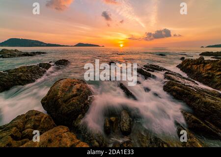 Langzeitbelichtung Bild der dramatischen Himmel Seestück mit Felsen in Der Vordergrund Sonnenuntergang oder Sonnenaufgang über Meer Landschaft Hintergrund Stockfoto