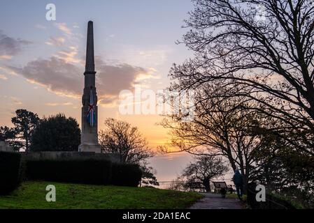 Sonnenaufgang am Gedenktag Sonntag 2020 am Southend war Memorial mit Blick auf die Themse Mündung. Person, die einen Hund am frühen Morgen während des Lockdown läuft Stockfoto