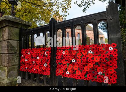 Gehäkelte Mohnblumen am Tor zum Scottish Poppy Appeal Remembrance Day, Prestonkirk Pfarrkirche, East Linton, East Lothian, Schottland, Großbritannien Stockfoto