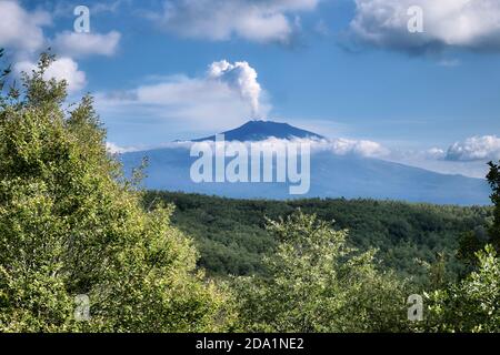 Eine Rauchsäule aus den Gipfelkrater des Vulkans Ätna, die sich über den Wäldern des Nebrodi-Parks und den niedrigen Wolken, Sizilien, erhebt Stockfoto