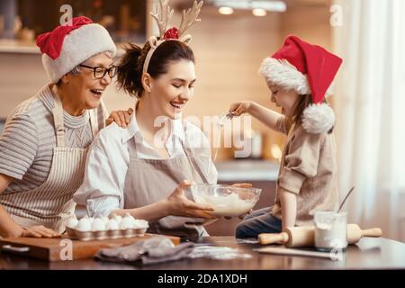 Frohe Weihnachten und frohe Feiertage. Familienzubereitung Urlaub Essen. Oma, Mutter und Tochter kochen Kekse. Stockfoto