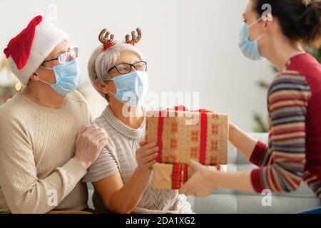 Menschen mit Geschenken tragen Gesichtsmasken während Coronavirus und Grippe Ausbruch an Weihnachten. Schutz vor Viren und Krankheiten, Quarantäne zu Hause. COVID-2019 Stockfoto