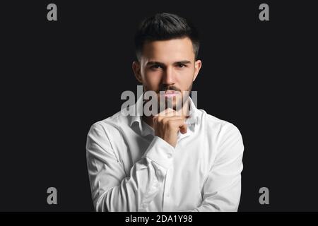 Modische junge Mann auf dunklem Hintergrund Stockfoto