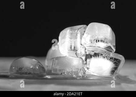 Schmelzende Eiswürfel auf dem Tisch. Schwarzer Hintergrund. Stockfoto