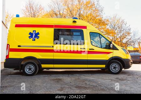 Zaporozhye/Ukraine- November 08 2019 :Gelber Krankenwagen steht in der Nähe des Krankenhausgebäudes.Seitenansicht eines Autos. Stockfoto